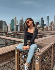 Me sitting on the Brooklyn Bridge with the New York skyline behind me.